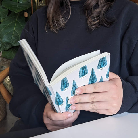 Woman holding open peacock design journal.
