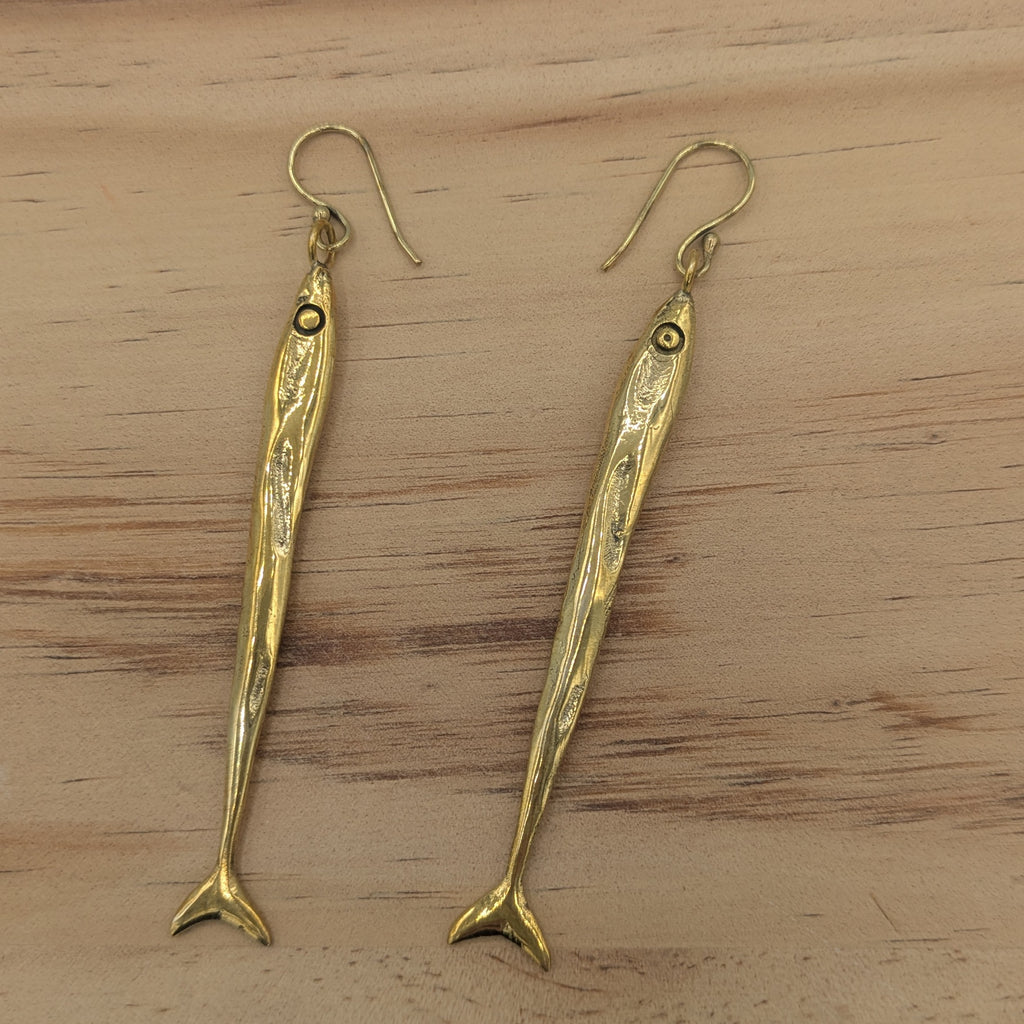 Gold fish-shaped earrings on a wooden surface
