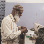 Load image into Gallery viewer, Artisan working on a sewing machine in a workshop setting

