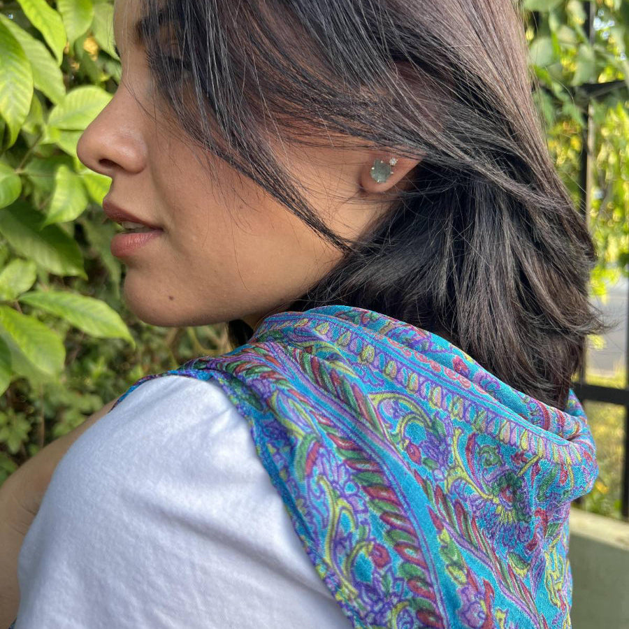 Woman wearing a colorful scarf with a blurred green outdoor background