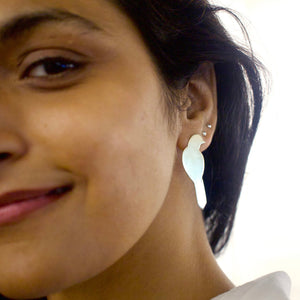 Close-up of a woman wearing a shiny gold toned bird earring with a blurred background