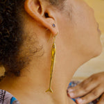 Load image into Gallery viewer, Close-up of a person wearing a gold colored fish-shaped earring.
