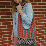 Load image into Gallery viewer, Woman with a colorful patterned tote bag on her shoulder against a brick wall
