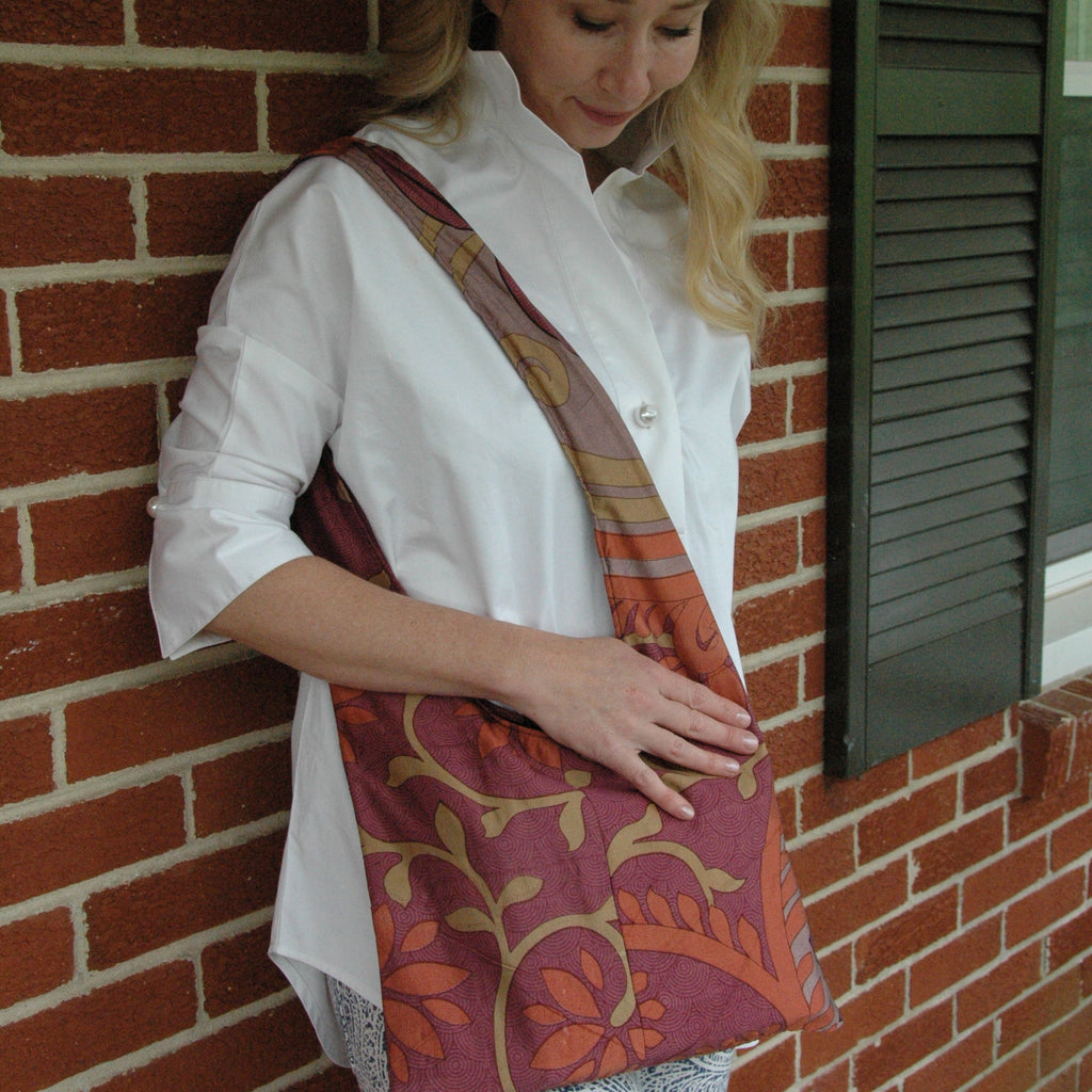 Woman with a colorful patterned tote bag on her shoulder against a brick wall