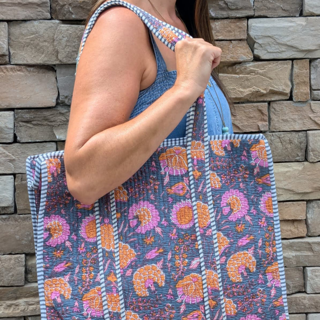 Person holding a colorful tote bag against a stone wall background