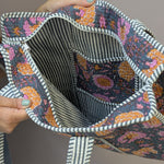 Load image into Gallery viewer, Hand holding a fabric bag with floral pattern and striped edge and lining
