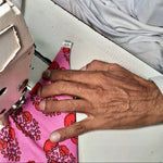 Load image into Gallery viewer, Person using a sewing machine with a close-up of hands and fabric.
