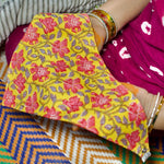 Load image into Gallery viewer, Yellow and pink floral bib with a colorful patterned background
