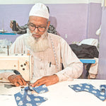 Load image into Gallery viewer, Man working on a sewing machine with fabric pieces in front of him.
