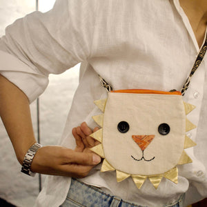 Person holding a small bag with a lion face design.