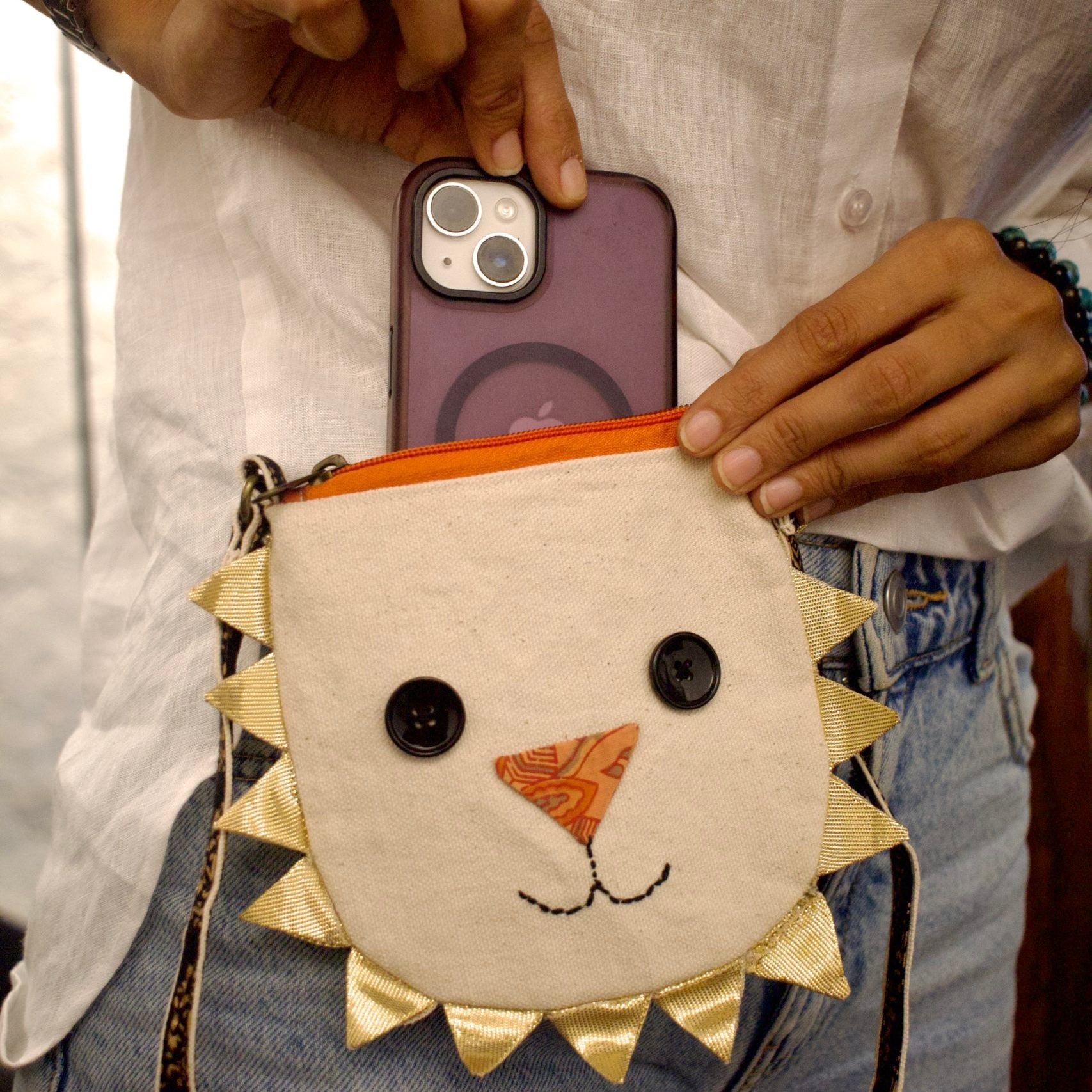 Person holding a phone with a lion-themed pouch