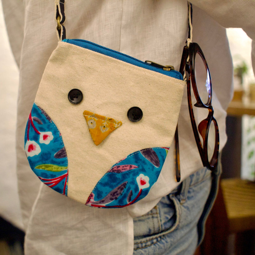 Handmade owl-shaped bag with blue and floral patterns, worn by a person.