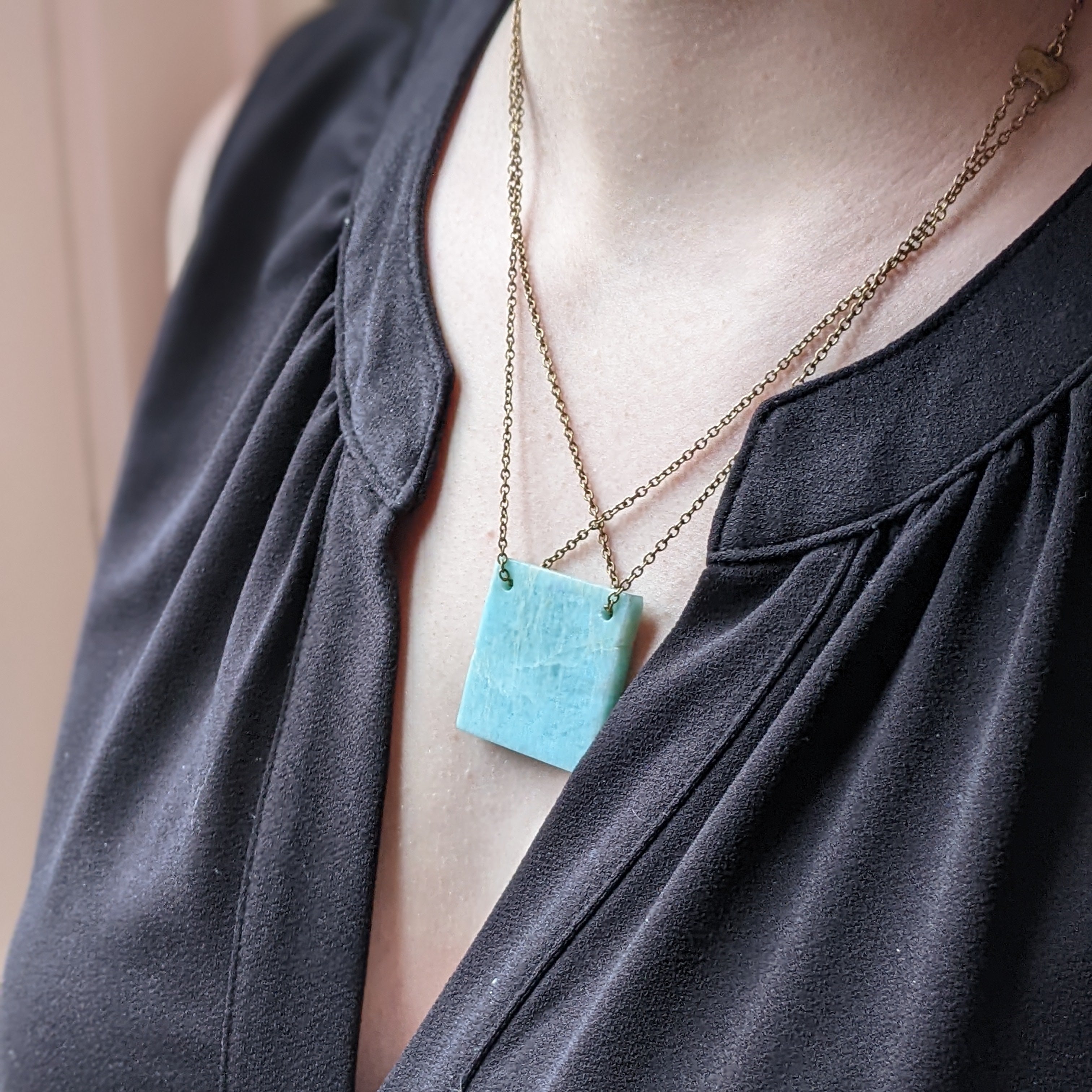 Necklace with a turquoise colored pendant on a black top