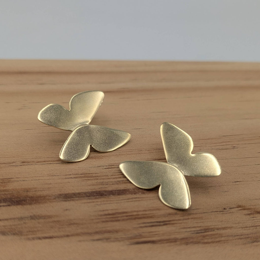 Pair of gold butterfly-shaped earrings on a wooden surface