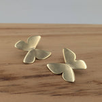 Load image into Gallery viewer, Pair of gold butterfly-shaped earrings on a wooden surface
