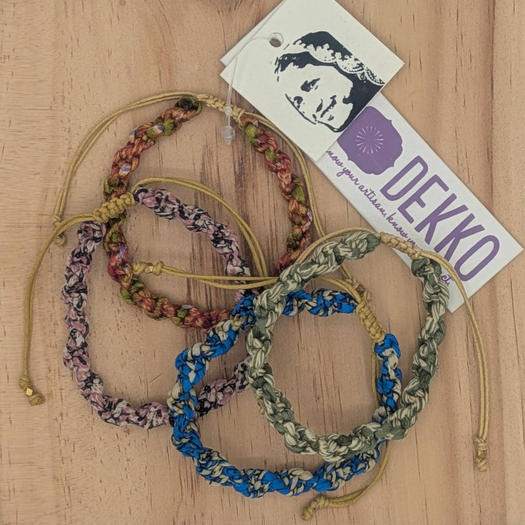 Four colorful bracelets on a wooden background with a tag labelled Dekko 