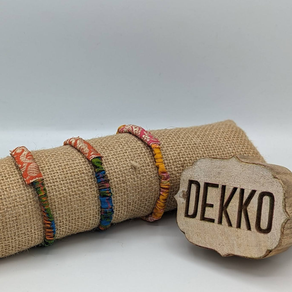 Decorative roll of burlap with thin scruncies made with colorful ribbon and a 'DEKKO' label on a white background