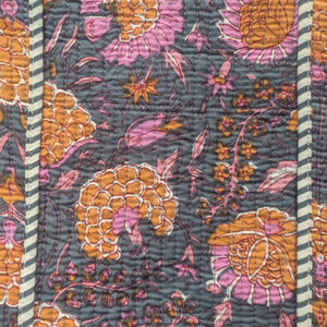 Close-up of a floral patterned fabric with orange, pink, and purple colors on a dark background.
